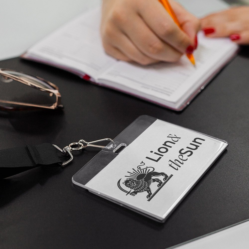 Lion & The Sun staff ID badge on desk beside staff member writing in notebook